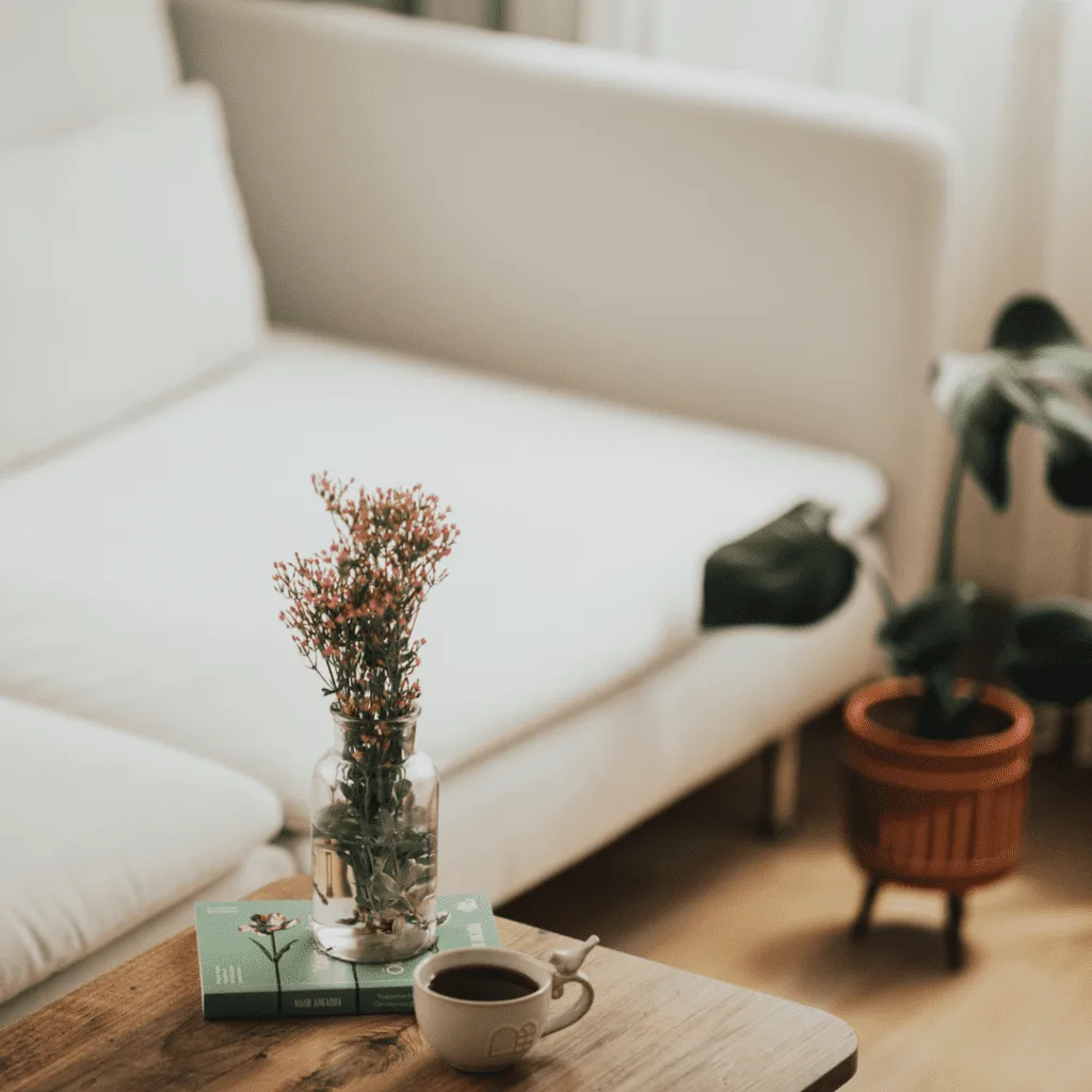 Cozy living room with a fresh, clean sofa, a small potted plant, and a cup of coffee on a wooden table.